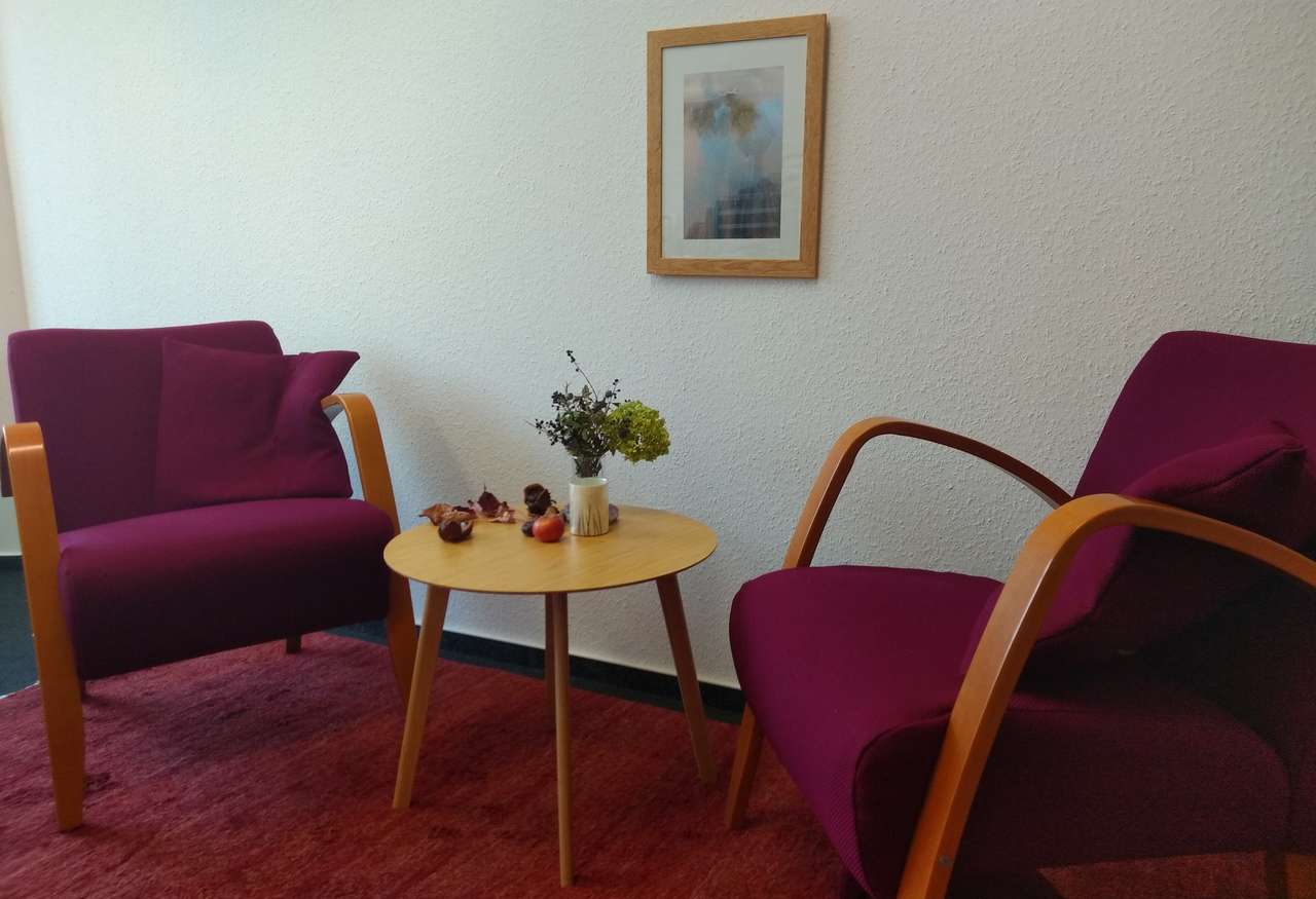 Beratungsraum mit zwei roten Sesseln und einem kleinen Tisch